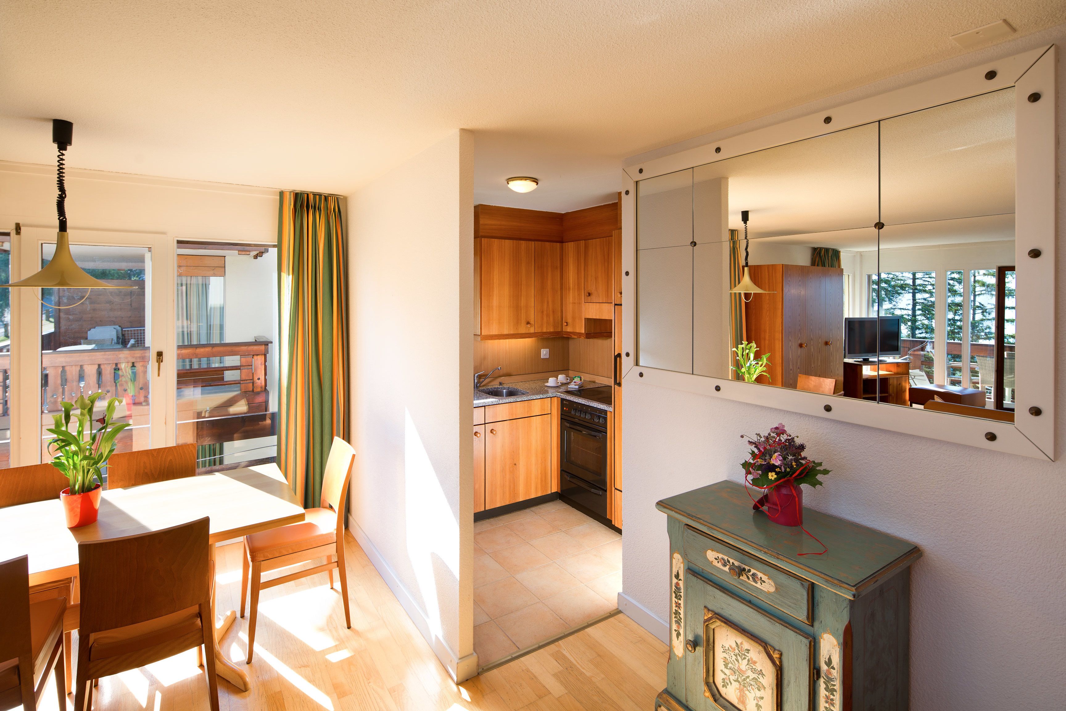 A modern kitchen with wooden cabinets, a dining area with a table and chairs, and a view of the outdoors.