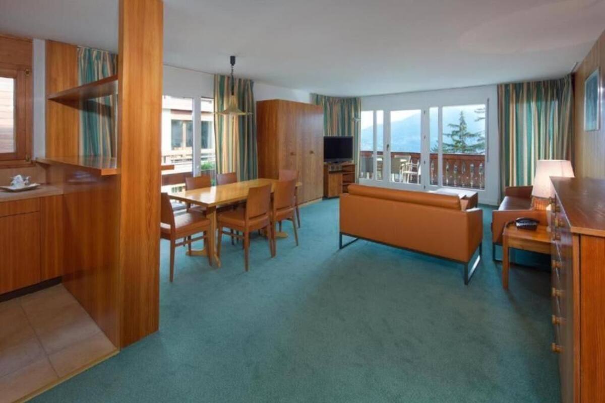Een moderne hotelkamer met een zithoek, een bank, een televisie en een balkon met uitzicht.