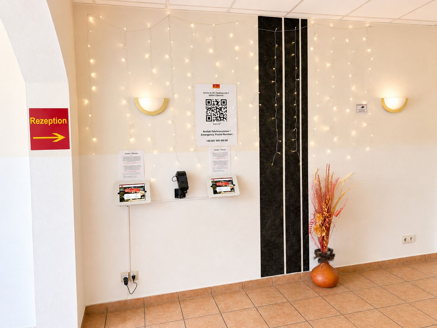 A reception area with a directional sign, a QR code, and a plant.