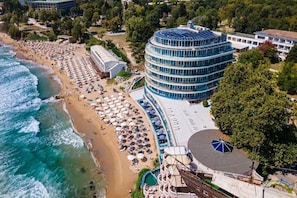 A coastal hotel with a beach, a pool, and a circular building with a blue roof. - Sirius Beach (Varna)