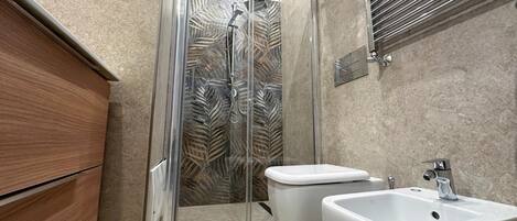 A modern bathroom with a glass shower enclosure, a toilet, and a sink.