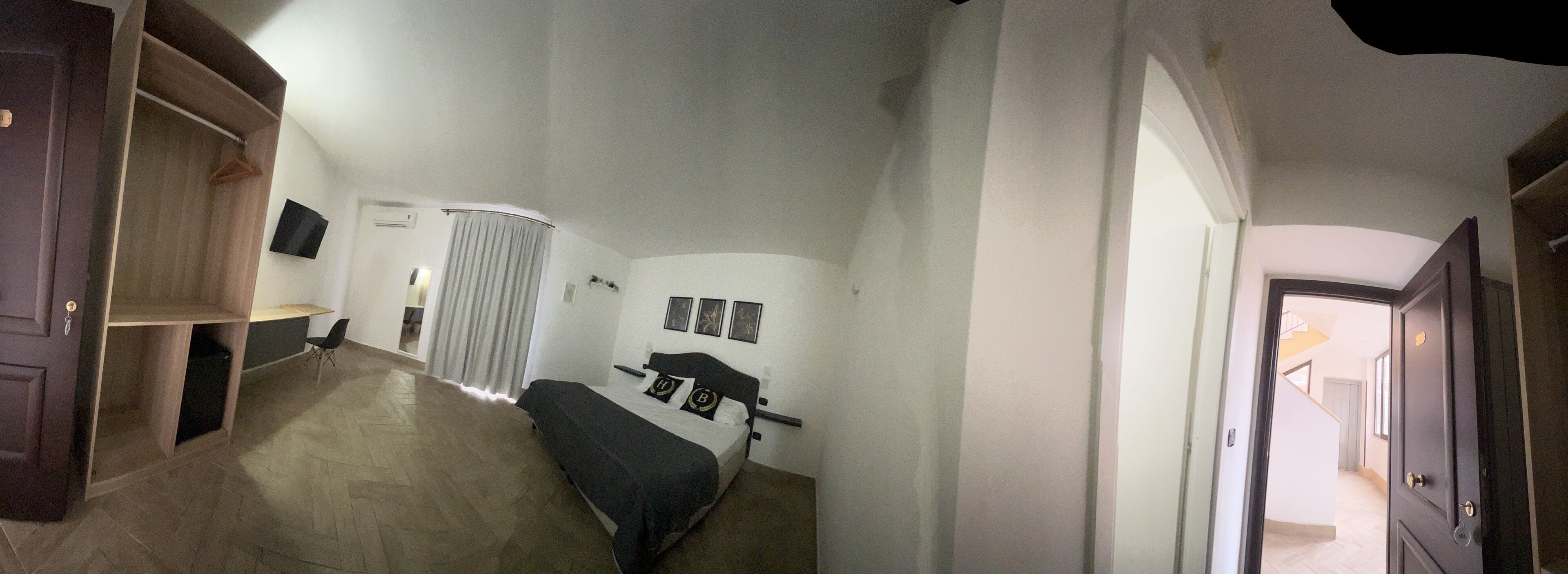 Une chambre à coucher comprenant un lit, une armoire, un téléviseur et une salle de bain avec un rideau de douche.