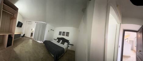 A bedroom with a bed, a wardrobe, a TV, and a bathroom with a shower curtain.