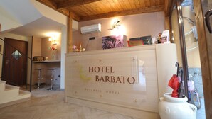 A reception desk with 'HOTEL BARBATO BUSINESS HOTEL' signage, wooden flooring, and a wooden ceiling. - Hotel Barbato (Naples)