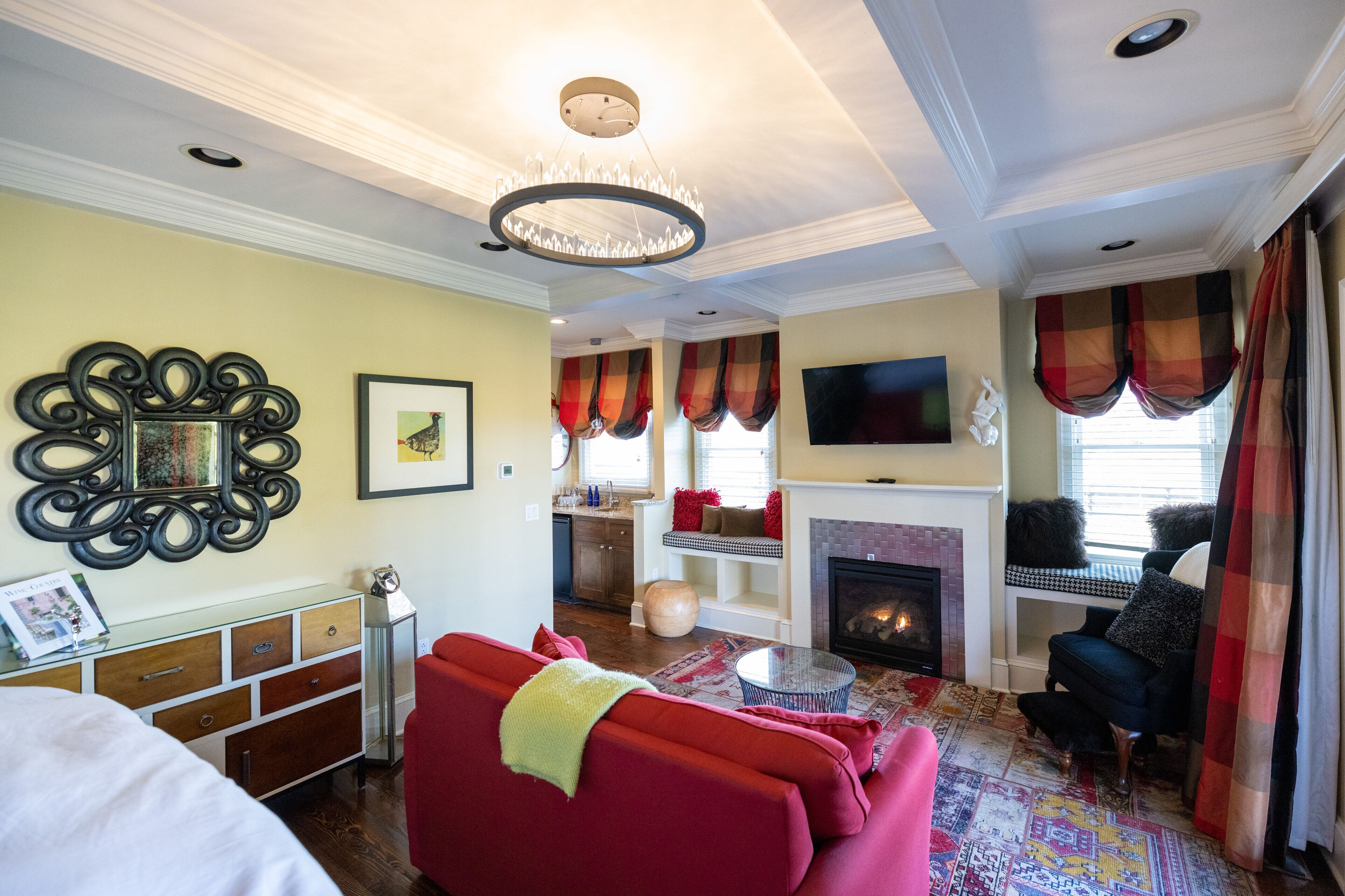 A living room with a fireplace, red sofa, and a television mounted on the wall.