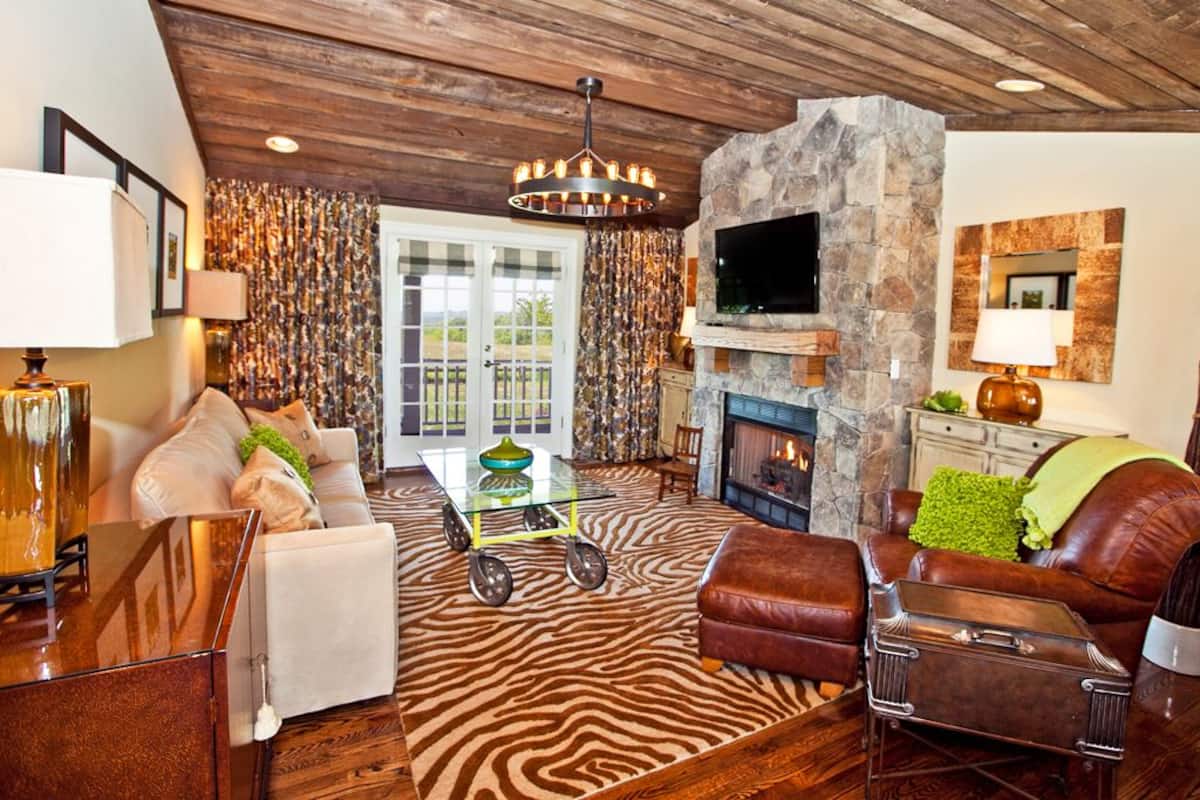A cozy living room with a stone fireplace, leather furniture, and a zebra-patterned rug.