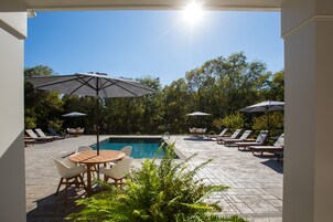 Una piscina al aire libre, sombrillas, sillones reclinables de piscina