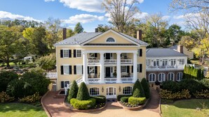 A large, two-story house with a central balcony, surrounded by well-maintained gardens and trees. - Inn at Willow Grove (Orange)