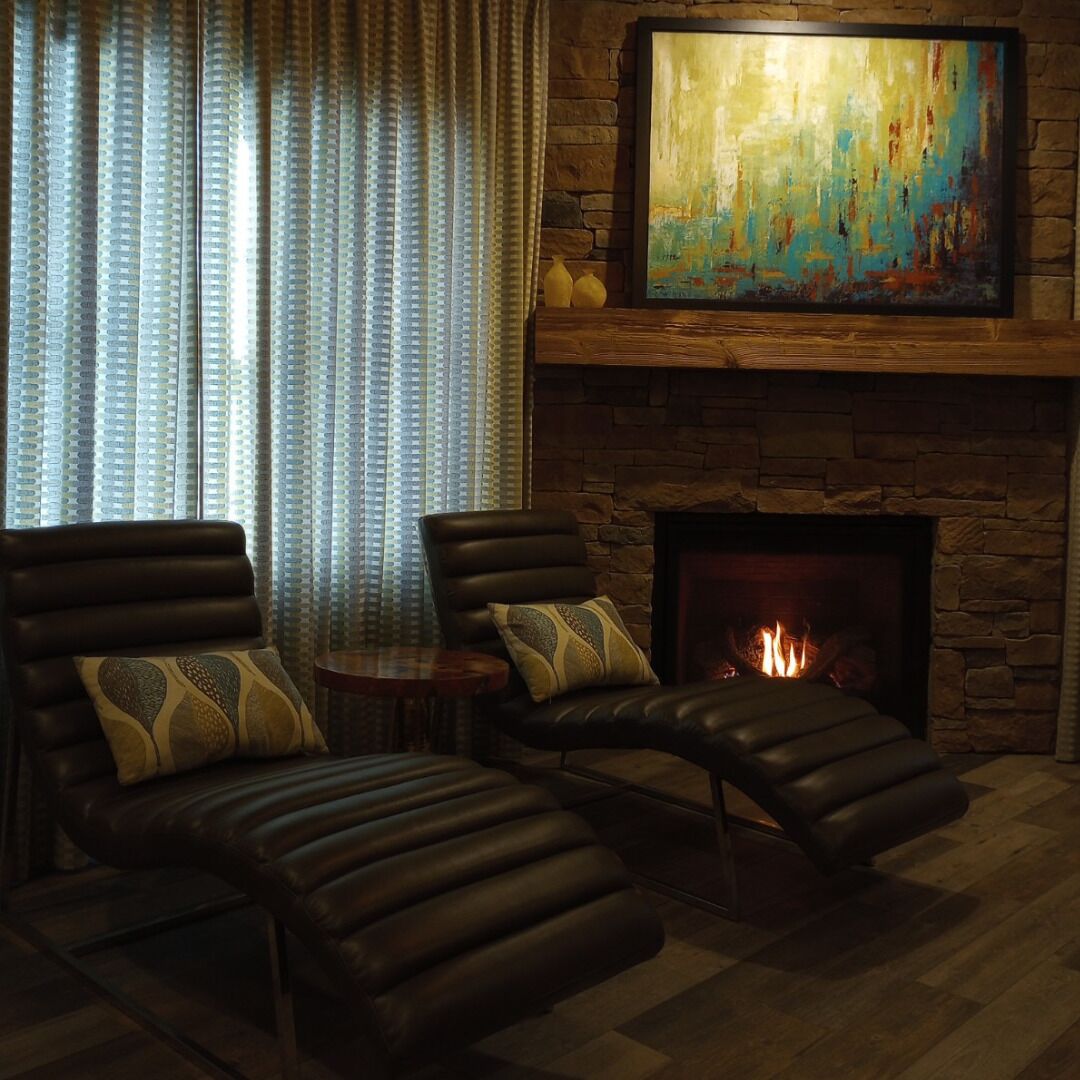 Una sala de estar acogedora con sofás de cuero, una chimenea y un cuadro abstracto grande en la pared.