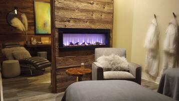 Un cuarto de spa con chimenea, una camilla de masaje, una silla y una pared de madera.