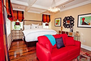 A bedroom with a large bed, a red sofa, and a chandelier. - Inn at Willow Grove (Orange)