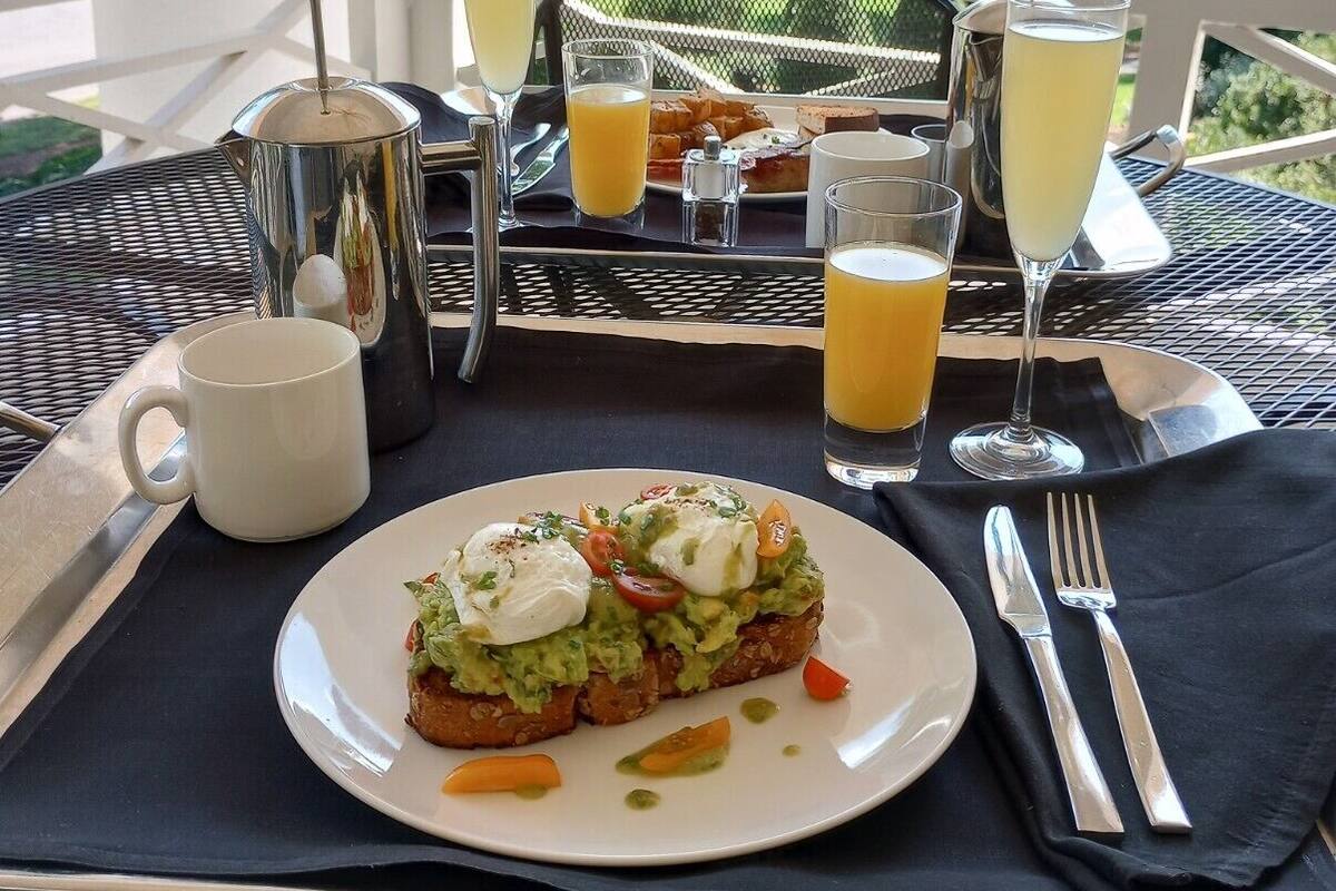 A breakfast setup on an outdoor table with a view of trees and hills.