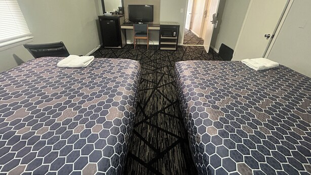 Une chambre d’hôtel avec deux lits, un bureau, une télévision et une armoire.
