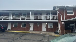 Un immeuble de deux étages en briques, doté d’un balcon blanc, d’un garage et d’un parking.