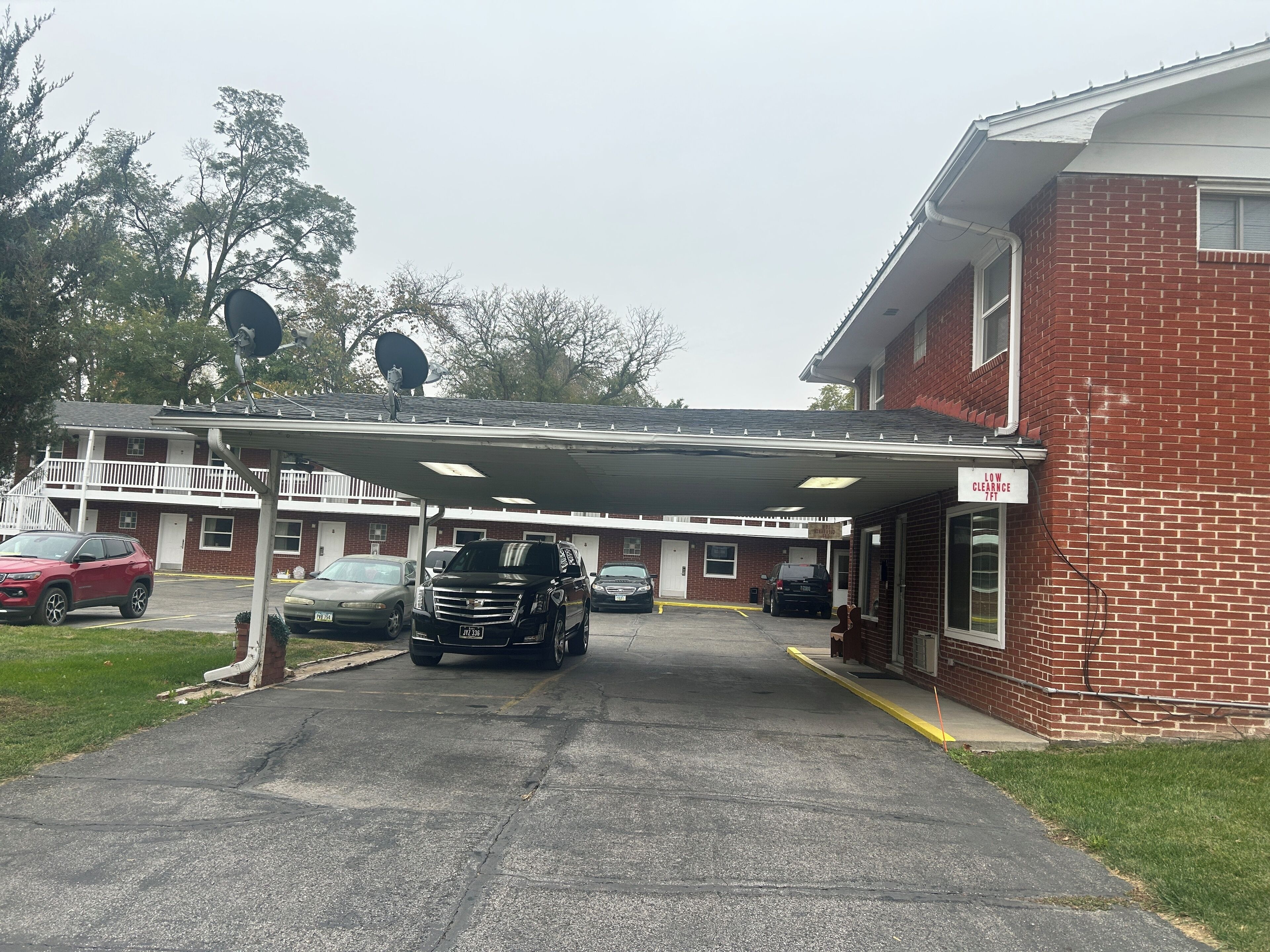 A building with a covered parking area, a sign indicating low clearance, and a brick facade.