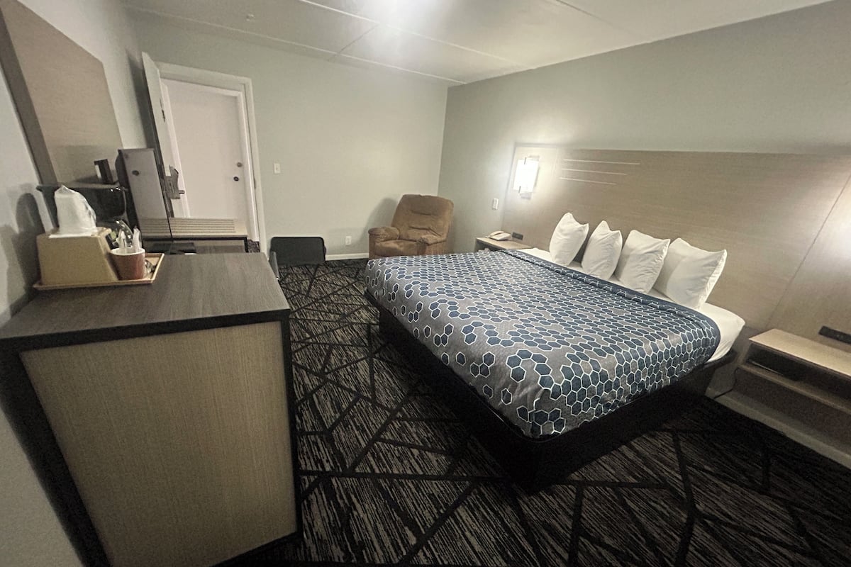 A hotel room with a bed, a desk, a chair, and a nightstand.