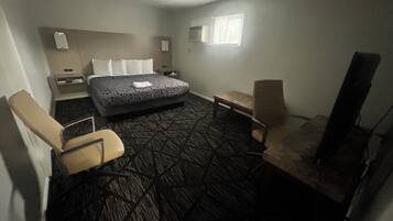Habitación de hotel con cama, dos sillas, una mesita, televisor y ventana.