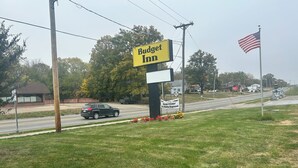 Une enseigne « Budget Inn » bien visible depuis la route, un VUS garé et une zone herbeuse parsemée de fleurs.