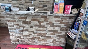 Un comptoir d’accueil avec un mur en pierre, un calendrier et divers dépliants d’information.