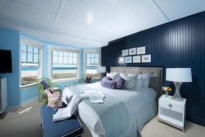 A bedroom with a bed, nightstand, and window with a view. - The Tides Beach Club (Kennebunkport)