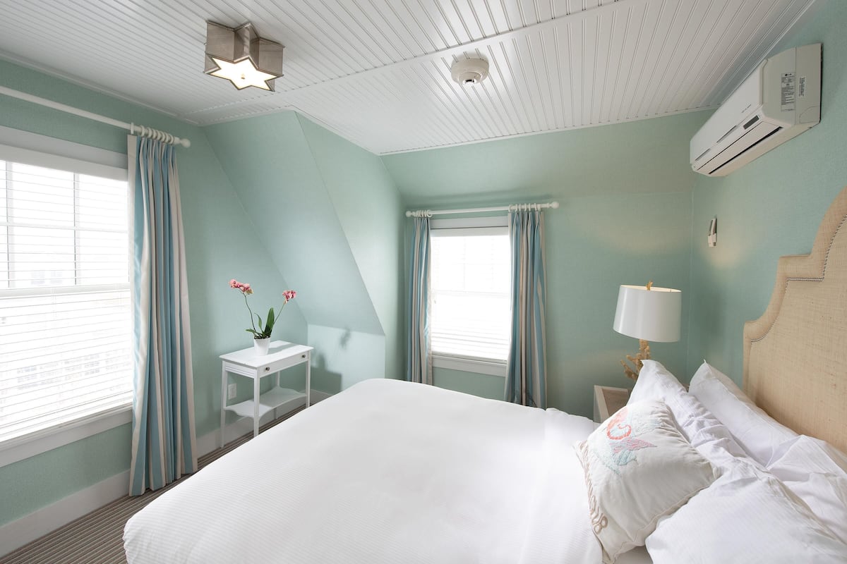 A bedroom with a bed, a nightstand, a lamp, and a window with curtains.