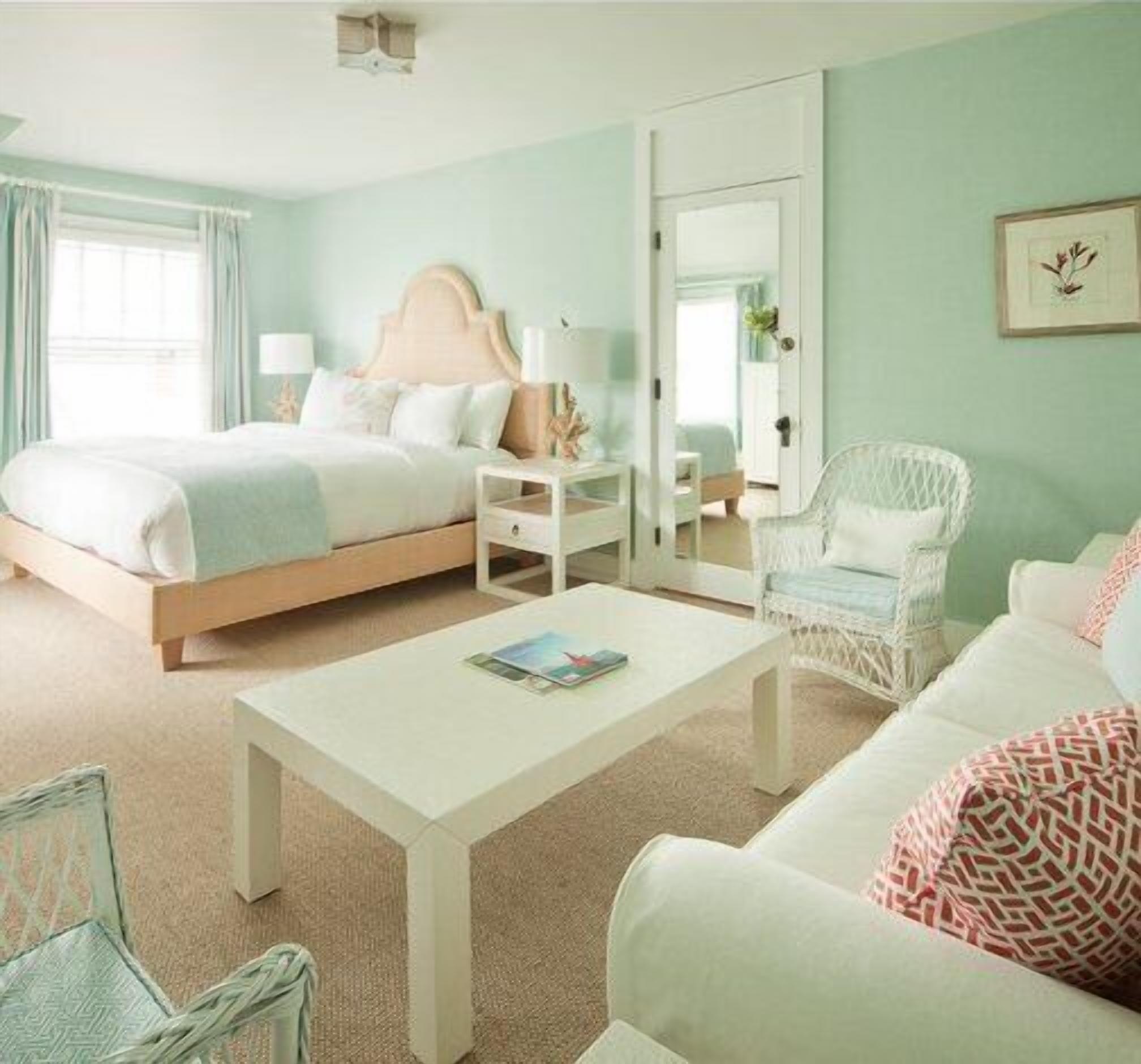 Un dormitorio con cama, mesita de noche, silla y una pequeña mesa con una revista.