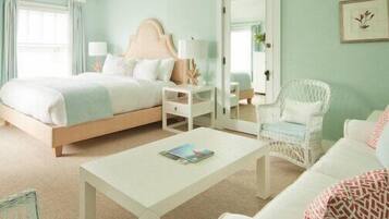 Un dormitorio con cama, mesita de noche, silla y una pequeña mesa con una revista.