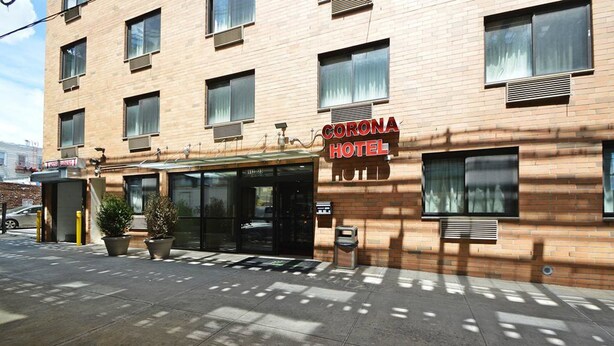 Um hotel com fachada de tijolos, janelas amplas e uma placa com a inscrição "Corona Hotel".