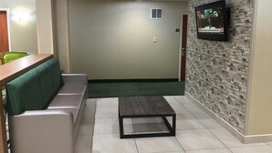 Uma sala de estar moderna com um sofá, uma mesa de centro e uma TV fixada numa parede com textura.