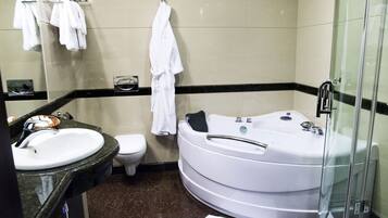 A bathroom with a sink, toilet, and a large bathtub.