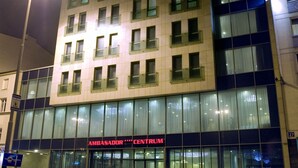 A hotel named "Hotel Ambassador" with a modern facade, large windows, and a visible entrance.