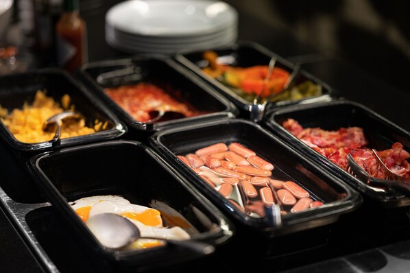 A buffet with various food options including eggs, sausages, and bacon. - Bohem Art Hotel (Budapest)