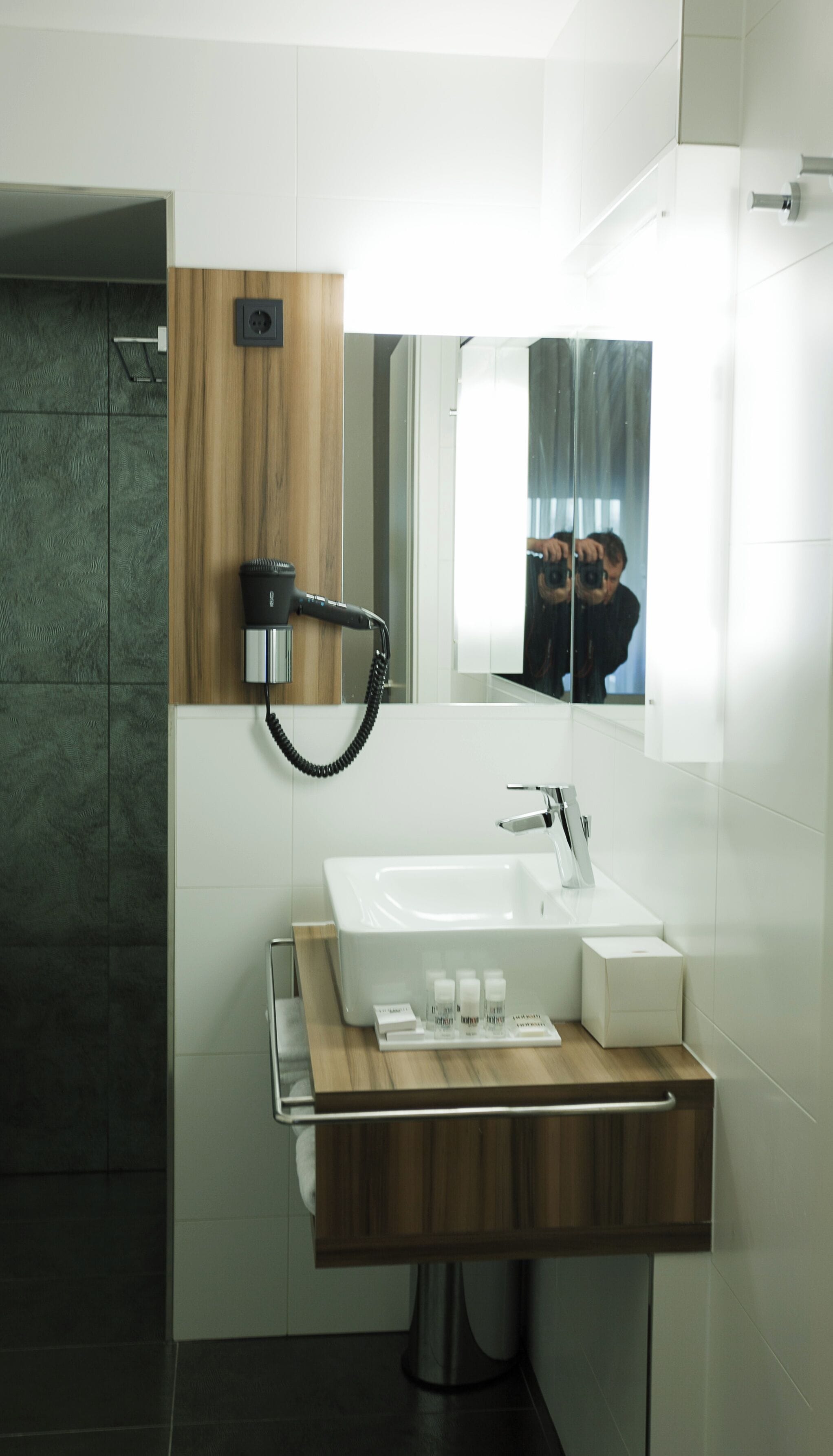 Une salle de bain moderne avec un meuble-lavabo en bois, un grand miroir et une douche intégrée.