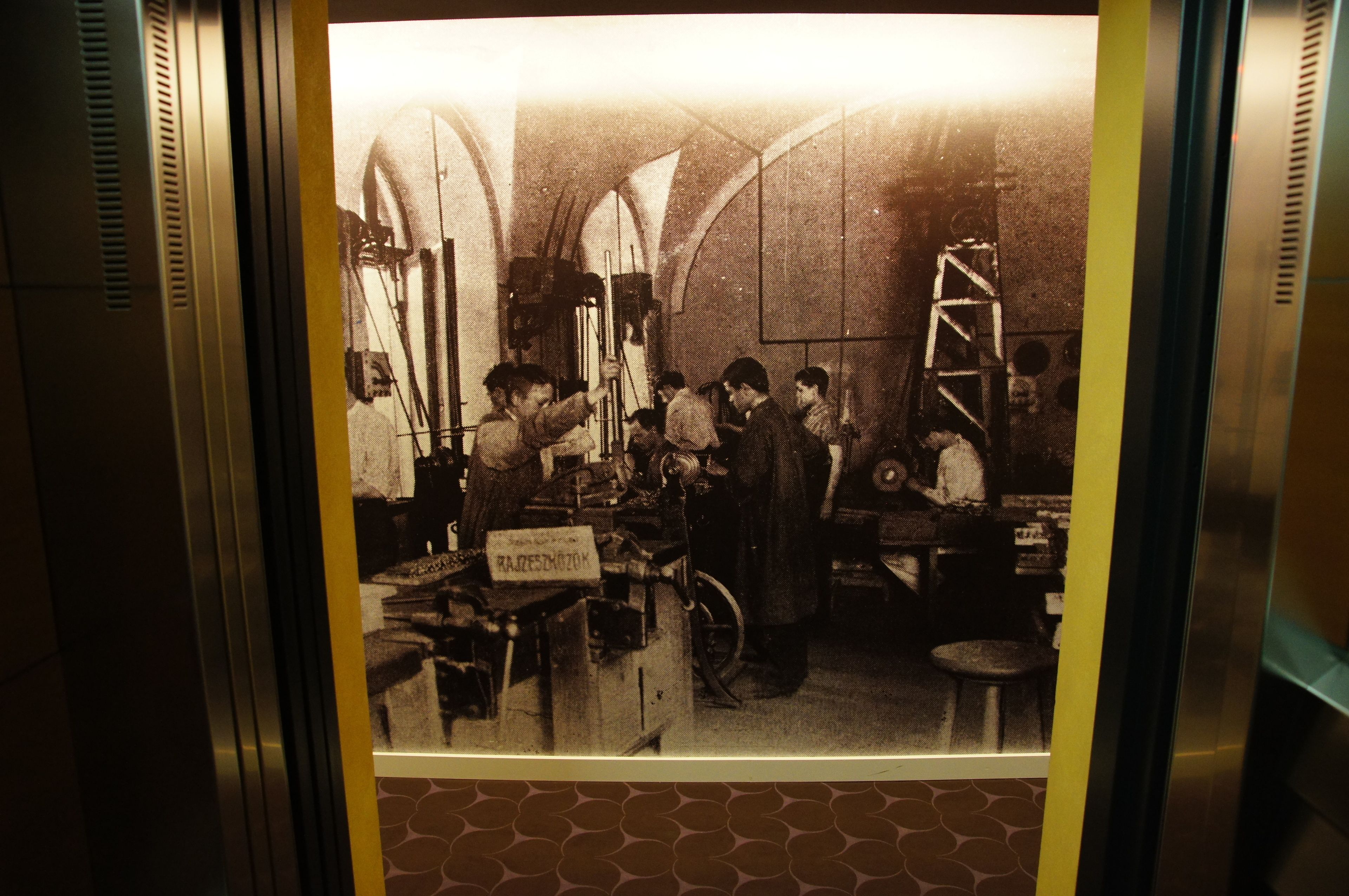 Une photographie ancienne représentant une pièce avec des plafonds en arc de cercle et une échelle, sur laquelle on peut voir une enseigne avec du texte.