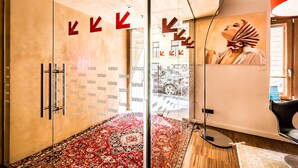 Et moderne hotelværelse med et stort spejl, en gulvtæppe med røde og hvide mønstre og et stort vindue med udsigt til gaden.
