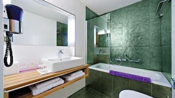 A modern bathroom with a large mirror, a sink, a bathtub, and a toilet.