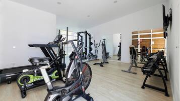 A gym with various exercise equipment including treadmills, stationary bikes, and weight machines.