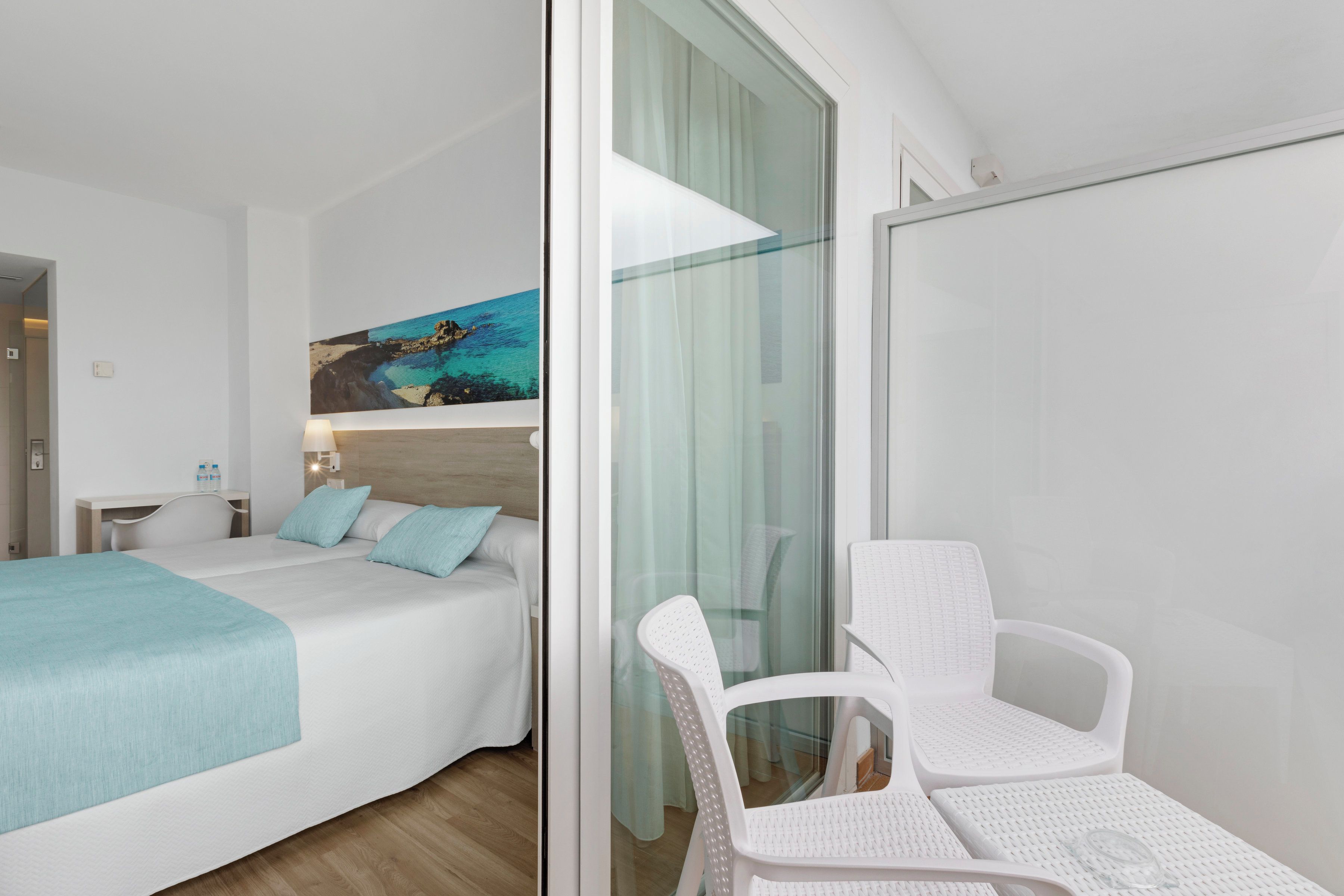 Una habitación de hotel moderna con una cama, un escritorio, una silla y un separador de vidrio.
