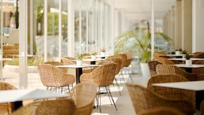 A sunlit outdoor cafe with wicker furniture and potted plants. - Alua Boccaccio (Alcúdia)