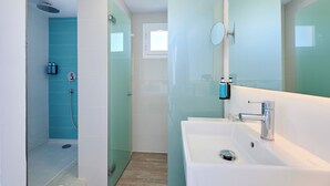 A modern bathroom with a glass shower enclosure, a white sink, and a large mirror. - Alua Boccaccio (Alcúdia)