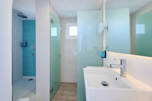 A modern bathroom with a glass shower enclosure, a white sink, and a large mirror. - Alua Boccaccio (Alcúdia)