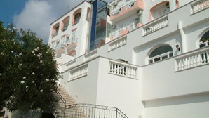 Un edificio de varios pisos con balcones, escaleras y un cielo despejado.