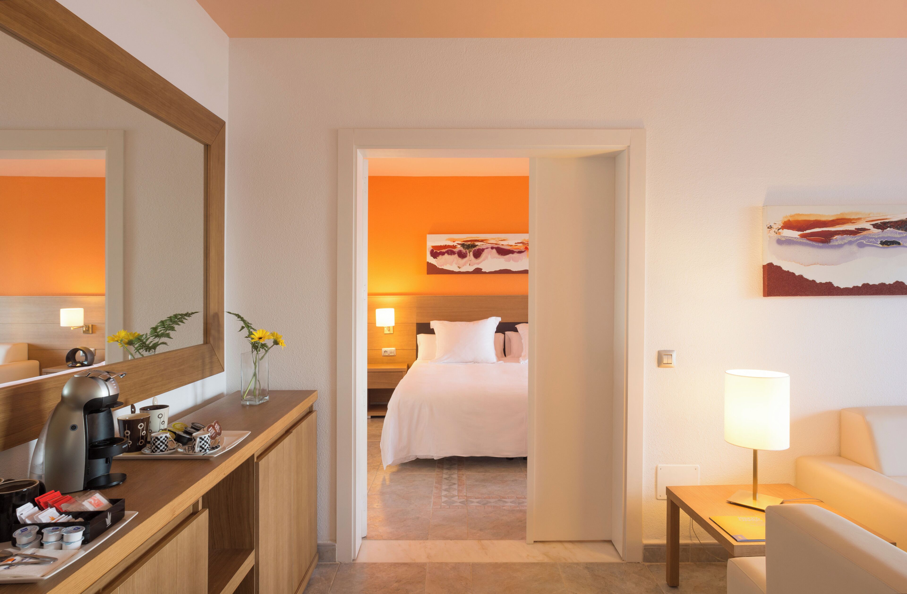 Ein Hotelzimmer mit Bett, Nachttisch, Lampe und einem großen Spiegel.
