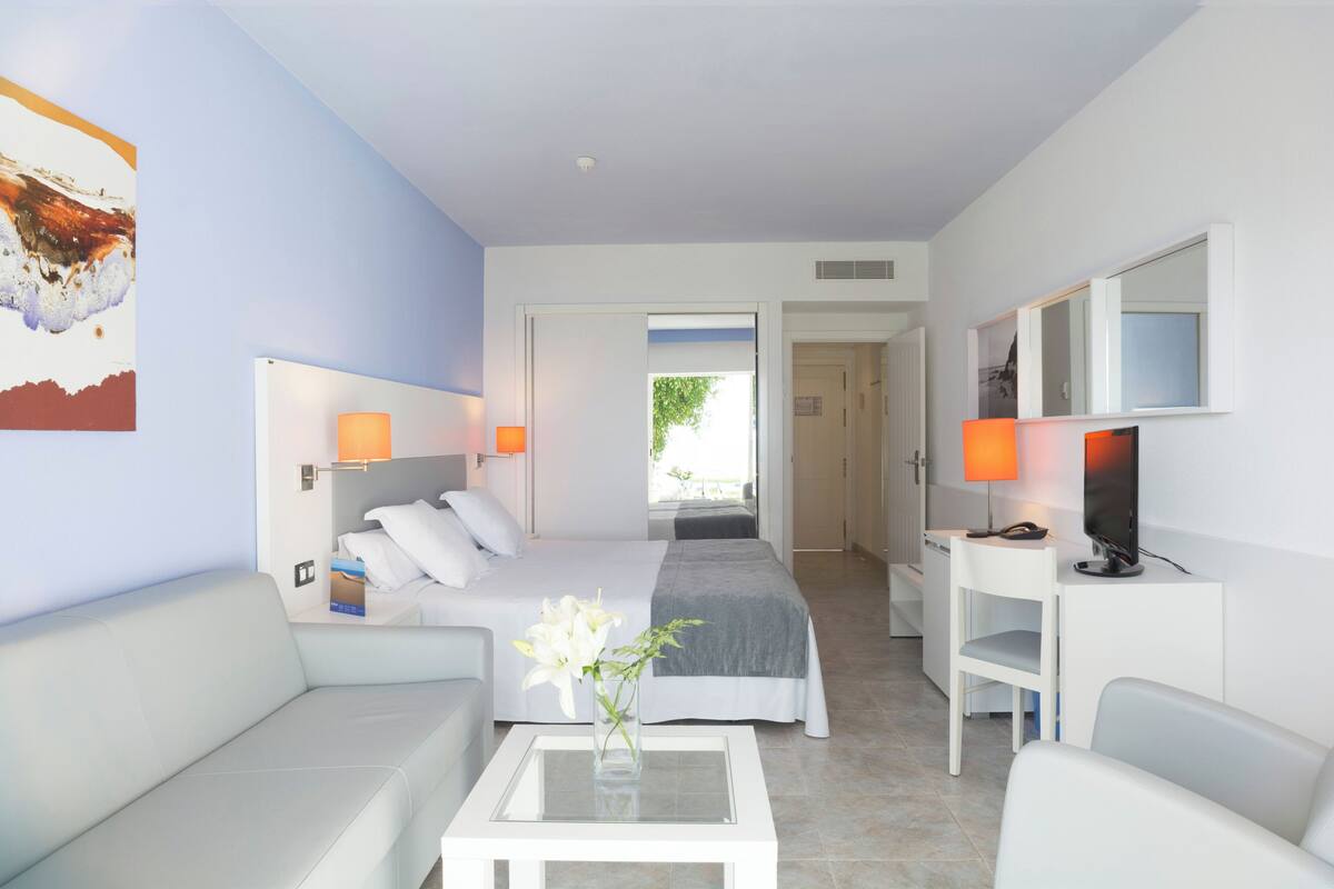 Habitació d'hotel moderna amb llit, escriptori, cadira, sofà i televisió.