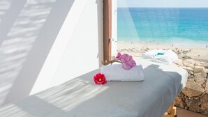 A room with a bed, a window overlooking a beach, and a stone wall. - Club Jandía Princess - All Inclusive (Pajara)