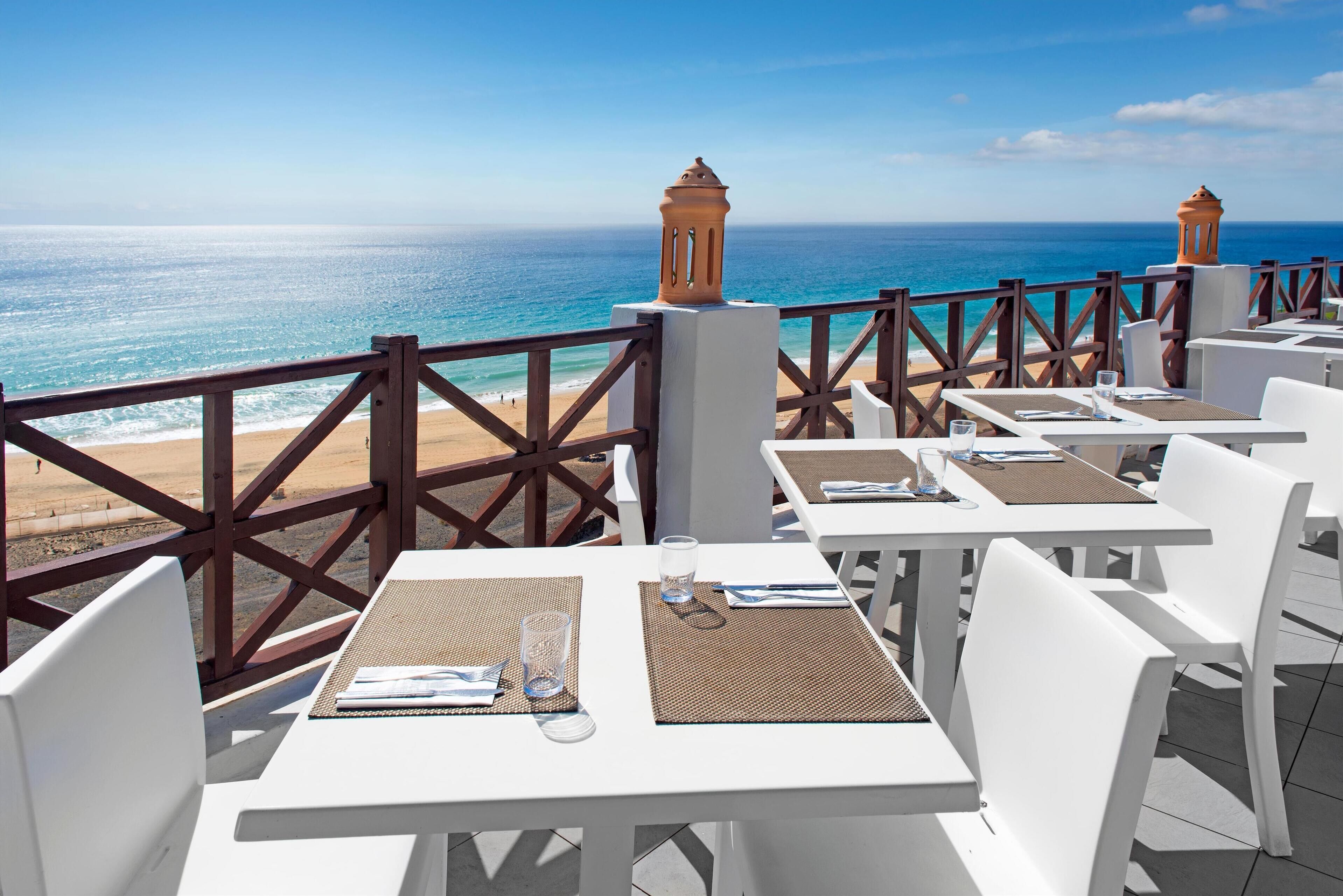 An outdoor seating area with tables and chairs overlooking the ocean.