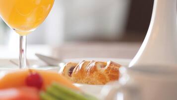 A breakfast setting with a croissant, orange juice, and fruit.