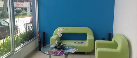 A room with a glass table, two green sofas, and a window with a view of a building labeled "nextel".