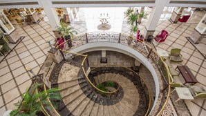 A grand spiral staircase with a marble floor, surrounded by a railing and potted plants. - IL Mercato Splash Aqua Park (Sharm El Sheikh)
