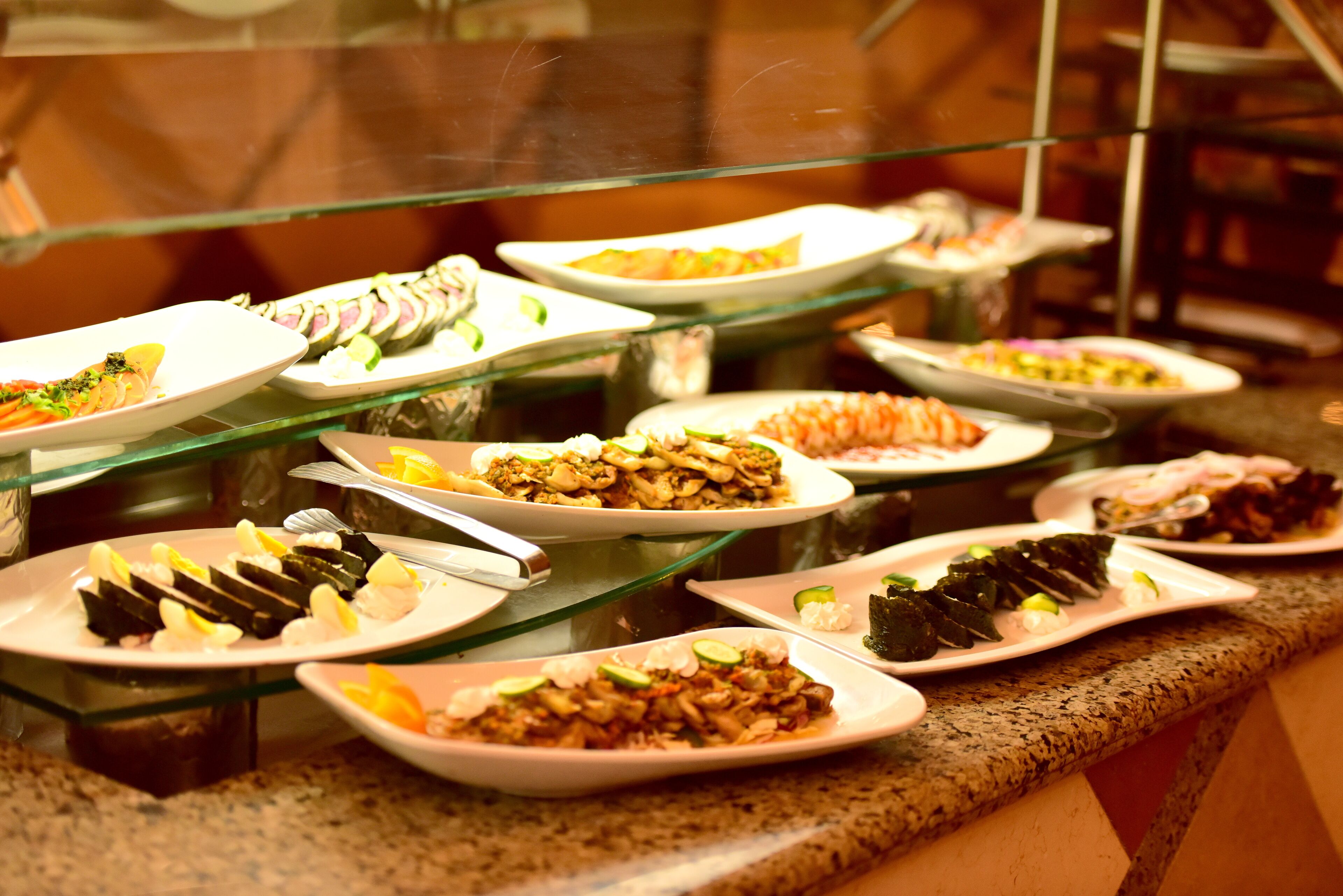 A buffet with various dishes including sushi, salads, and other prepared foods.